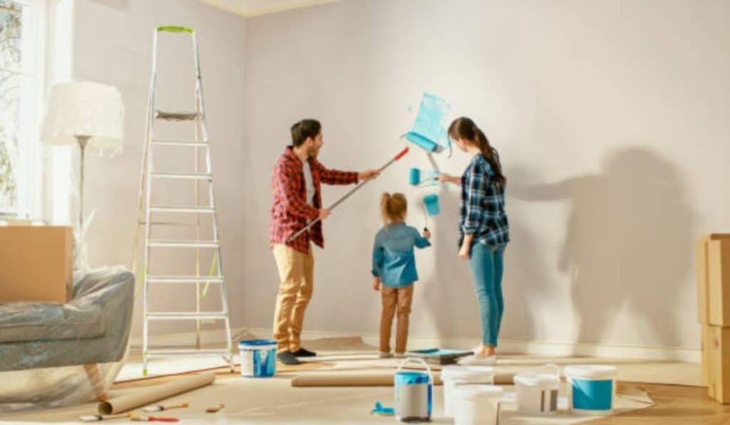 Family engaged in rental property maintenance, painting the interior of their home, showcasing practical landlord property management