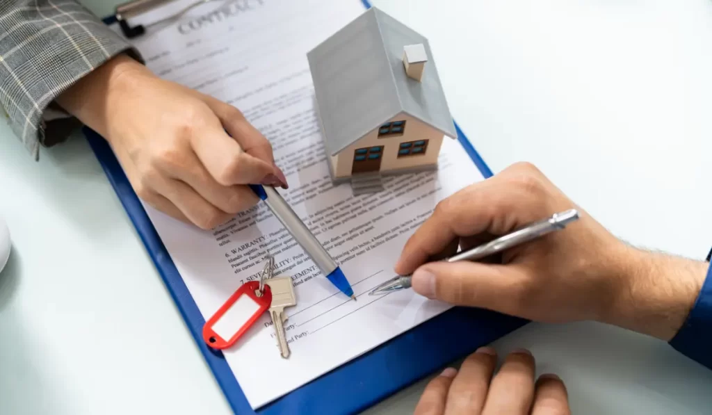 Right property manager reviewing and signing rental agreement with homeowner over keys and contract documents.