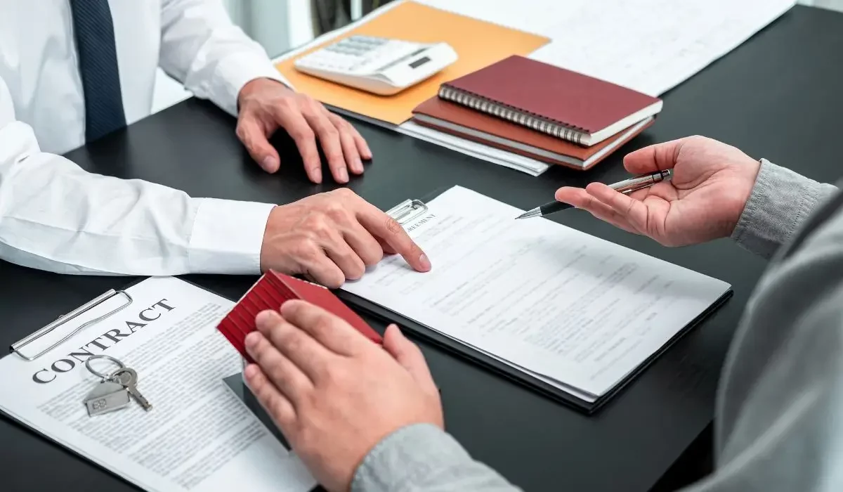 Two people reviewing and signing a rental contract with house keys and documents on the table, illustrating the importance of written policies for Los Angeles landlords.